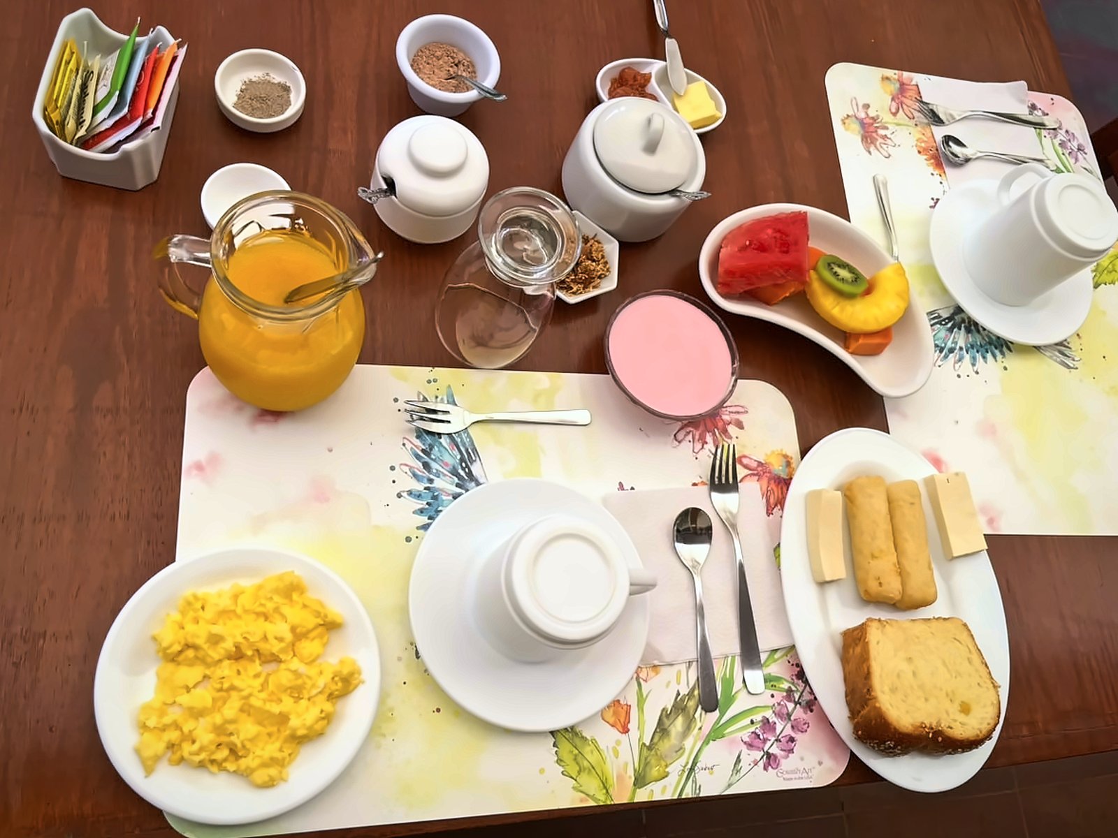 Desayuno servido en Mindo Real: huevos, jugo, frutas, pan y bebida caliente